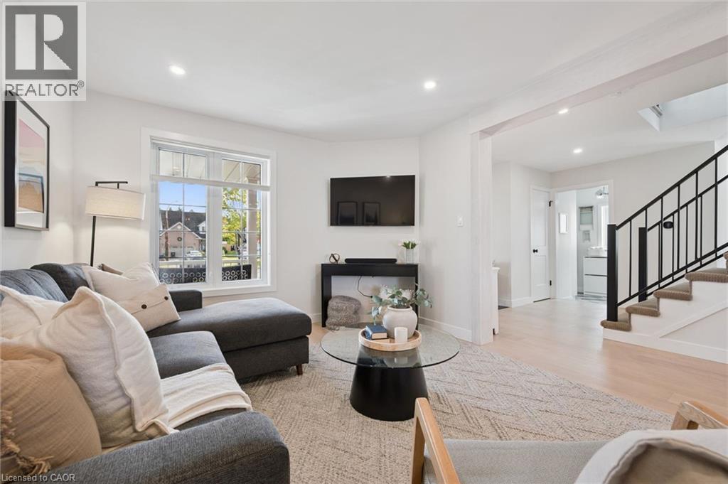 Recessed lighting, light wood-finish flooring, white walls, and a staircase with black metal railing - 6 Branwood Place, Kitchener, ON