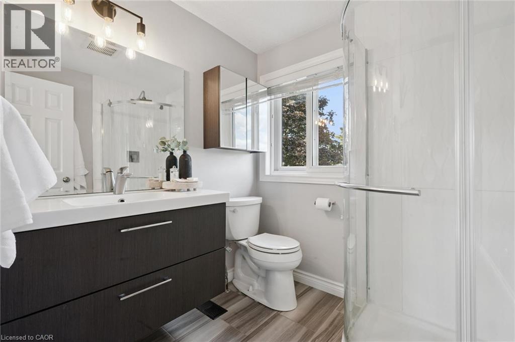 Modern vanity with integrated sink, tile flooring, and a glass-enclosed shower - 6 Branwood Place, Kitchener, ON