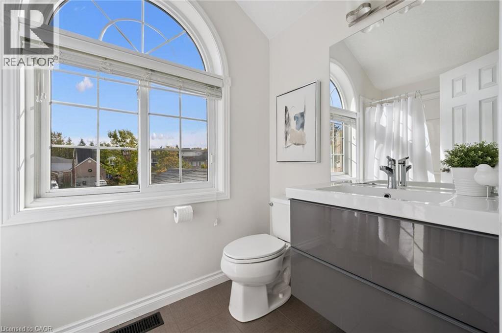 Arch-top window with grid pattern, a modern vanity with a white countertop, a rectangular undermount sink, and a chrome-finish faucet - 6 Branwood Place, Kitchener, ON
