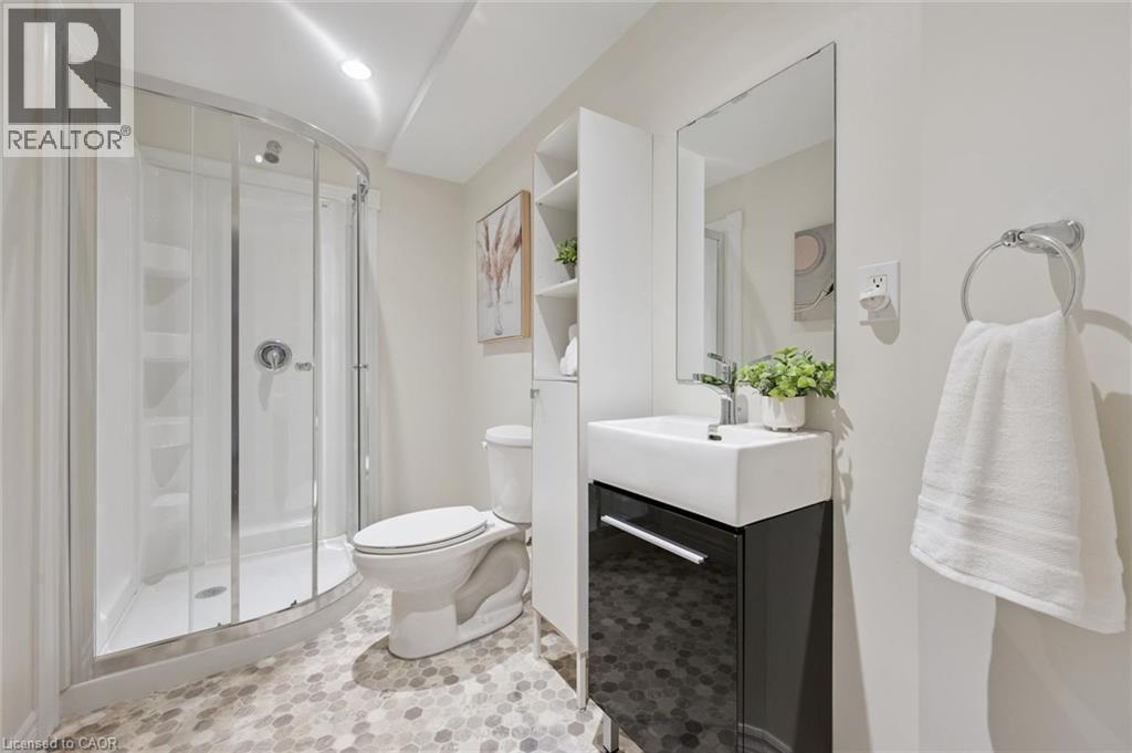 Curved glass shower enclosure, contemporary white toilet, vanity with integrated white sink, wall-mounted mirror, and hexagonal flooring - 6 Branwood Place, Kitchener, ON