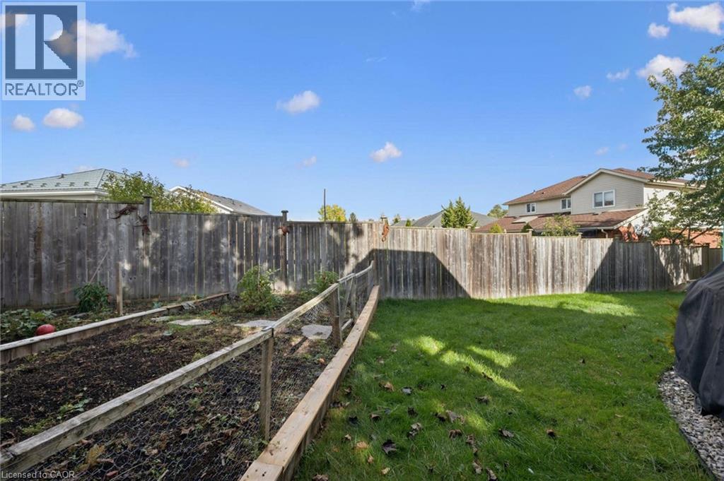 Expansive backyard featuring a manicured lawn, established garden beds, and a wood privacy fence - 6 Branwood Place, Kitchener, ON