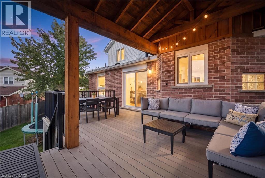 Covered outdoor deck with exposed wood beam ceiling, composite decking, and brick exterior wall - 6 Branwood Place, Kitchener, ON