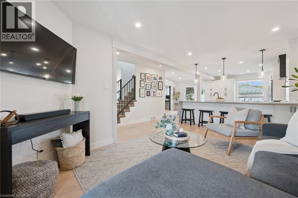 Recessed lighting, wood-finish flooring, staircase with dark metal railing, kitchen island with seating, and pendant lighting - 6 Branwood Place, Kitchener, ON