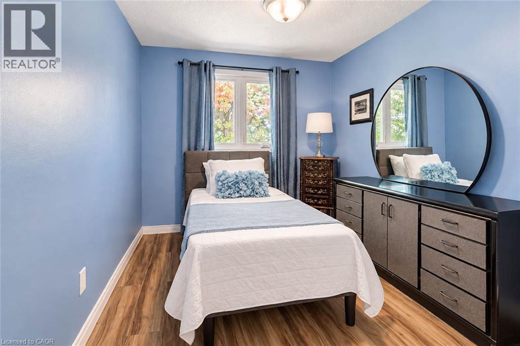 Wood-finish flooring, single window with drapes, built-in cabinetry with drawers, circular mirror, and ceiling-mounted light fixture - 327 Oprington Place, Kitchener, ON