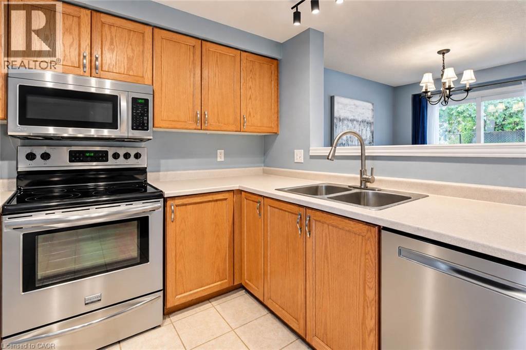 Kitchen featuring wood cabinetry, stainless steel appliances, a double basin sink, and track lighting - 327 Oprington Place, Kitchener, ON