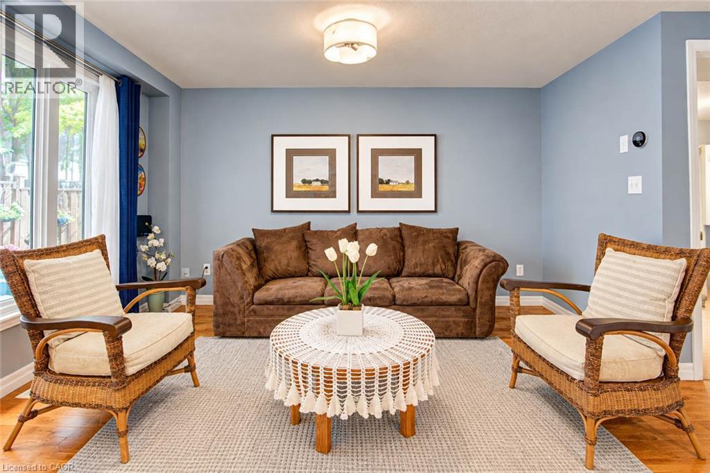 Hardwood-finish flooring, light blue wall paint, multiple windows, and a ceiling-mounted light fixture - 327 Oprington Place, Kitchener, ON