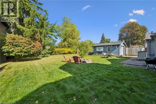 Expansive grass lawn, mature trees, built-in fire pit, detached garage, and concrete patio - 74 Selkirk Street, Cambridge, ON 