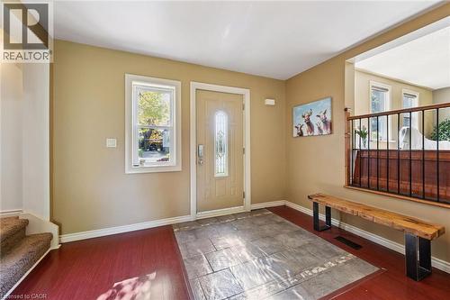 Entryway featuring a decorative glass panel door, an adjacent window, textured tile flooring, and wood-finish flooring - 74 Selkirk Street, Cambridge, ON 