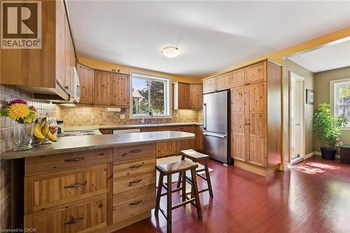 Kitchen featuring wood cabinetry, stainless steel refrigerator, tile backsplash, and wood-finish flooring - 74 Selkirk Street, Cambridge, ON 