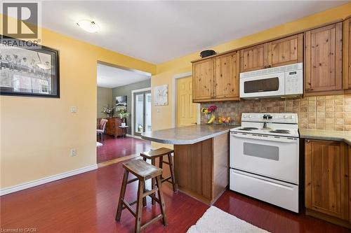 Kitchen featuring wood-finish flooring, wood cabinetry, a built-in microwave, and a tile backsplash - 74 Selkirk Street, Cambridge, ON 