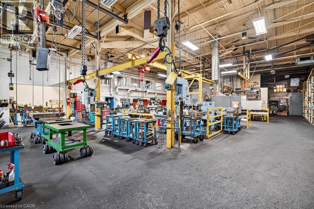 Industrial warehouse space featuring high ceilings, exposed structural steel trusses, overhead crane systems, high-intensity lighting fixtures, and concrete flooring - 47 Head Street, Hamilton, ON