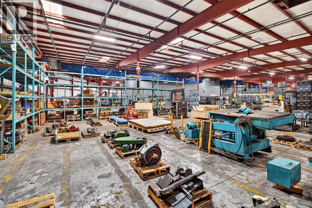 Industrial warehouse featuring a high-clearance open floor plan, exposed steel beam construction, concrete flooring, and suspended overhead lighting - 47 Head Street, Hamilton, ON