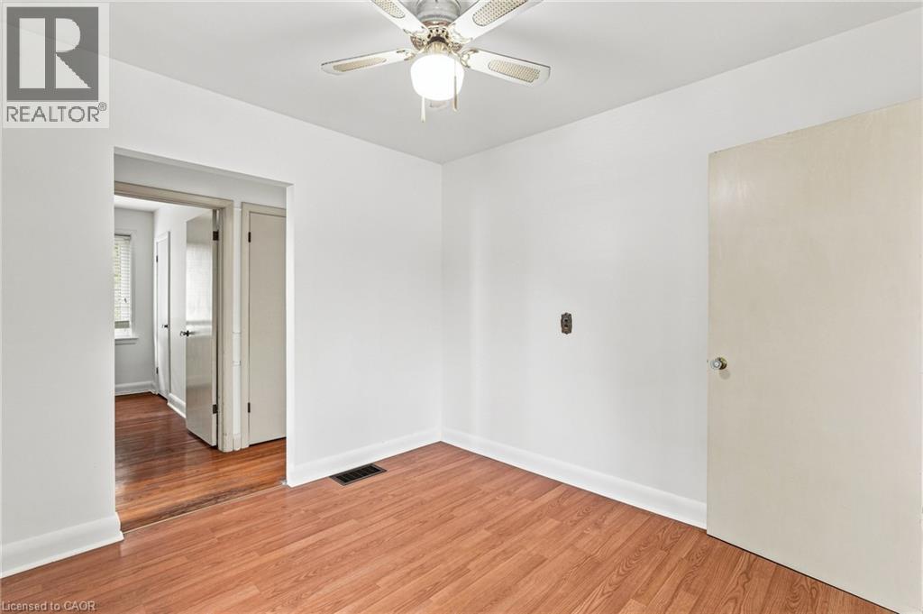 Room featuring wood-finish flooring, white walls, and a ceiling-mounted light fixture with a fan - 241 East 44Th Street, Hamilton, ON