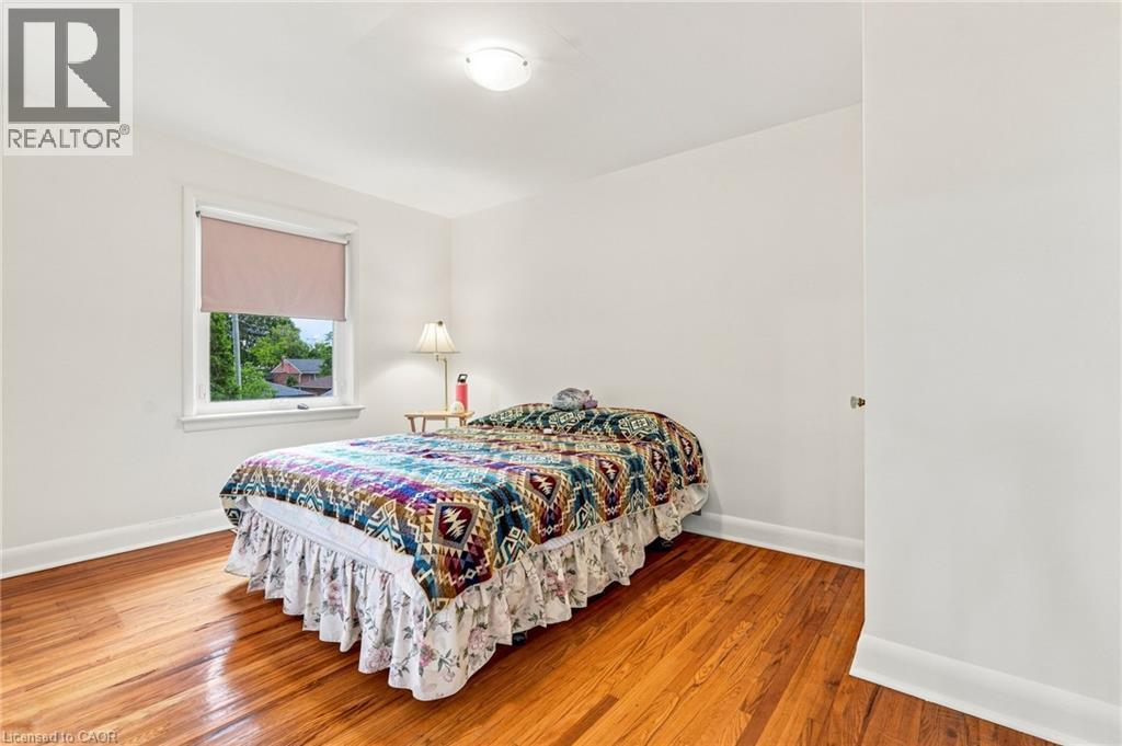 Neutral interior space featuring polished wood-finish flooring, white walls, and a single-pane window with an integrated roller shade - 241 East 44Th Street, Hamilton, ON