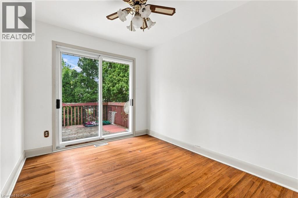 Room featuring wood-finish flooring, sliding glass door, and a ceiling fan with integrated light fixture - 241 East 44Th Street, Hamilton, ON