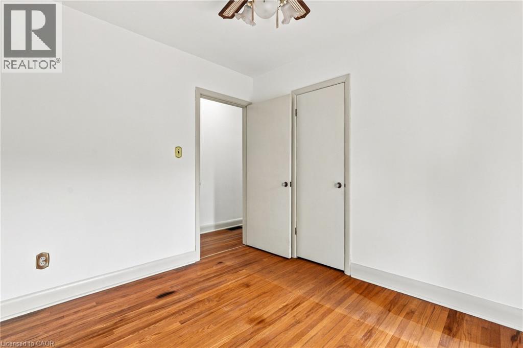 Wood-finish flooring, neutral wall tones, multi-panel doors, and an overhead flush-mount light fixture - 241 East 44Th Street, Hamilton, ON