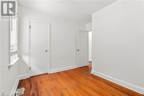 Interior space featuring wood-finish flooring, white walls, and a window with horizontal blinds - 241 East 44Th Street, Hamilton, ON 