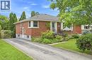 Red brick exterior featuring a hip roof, asphalt driveway, metal porch railings, and mature landscaping - 241 East 44Th Street, Hamilton, ON 