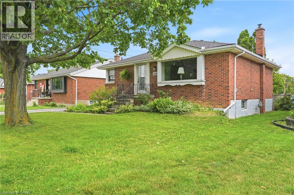 Exterior featuring red brick masonry, a brick chimney, a front bay window, and a wrought-iron entrance railing - 241 East 44Th Street, Hamilton, ON