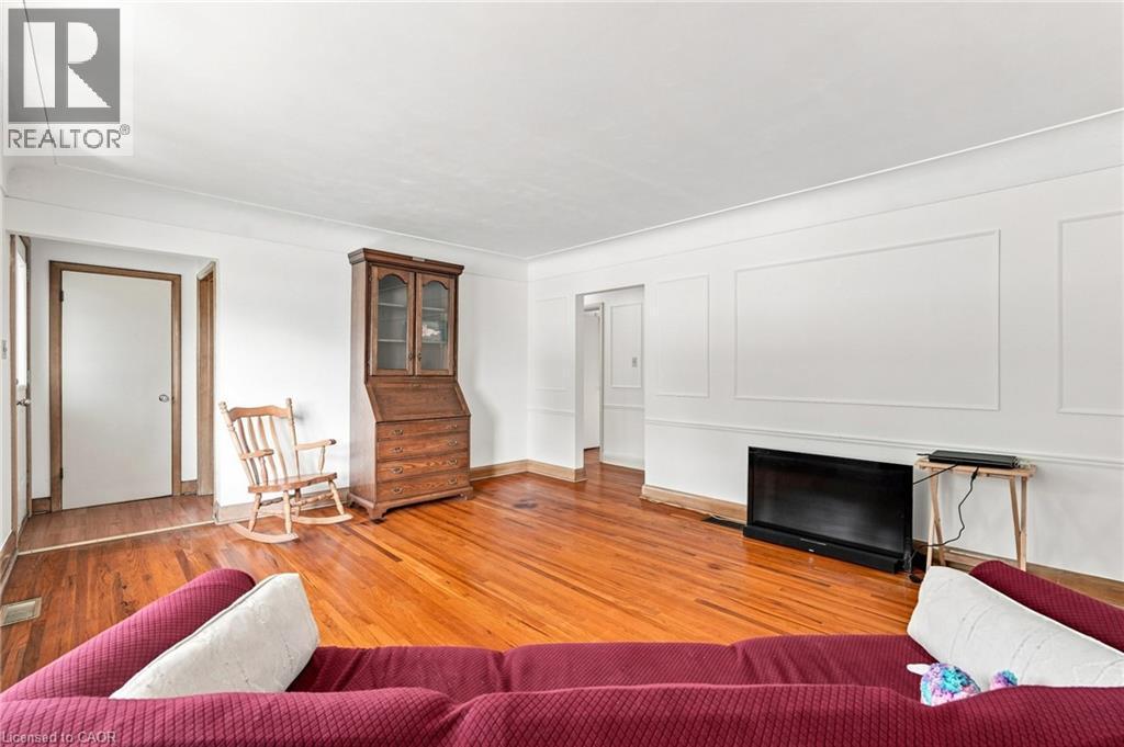 Living space featuring wood-finish flooring, wall paneling, and neutral paint - 241 East 44Th Street, Hamilton, ON