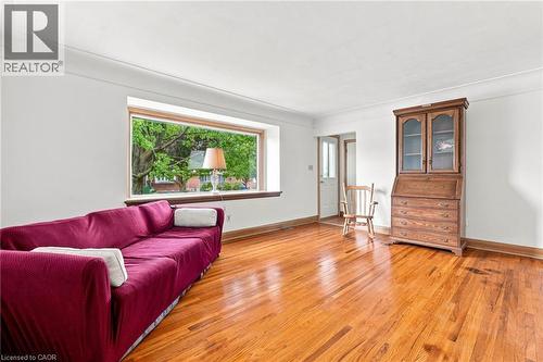 Spacious room featuring polished wood-finish flooring, white walls, and a large picture window - 241 East 44Th Street, Hamilton, ON 