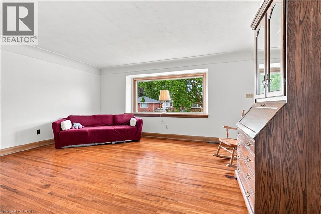 Living area featuring wood-finish flooring, white walls, crown molding, and a large picture window - 241 East 44Th Street, Hamilton, ON