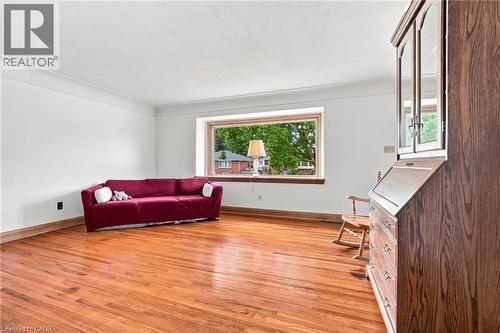 Living area featuring wood-finish flooring, white walls, crown molding, and a large picture window - 241 East 44Th Street, Hamilton, ON 