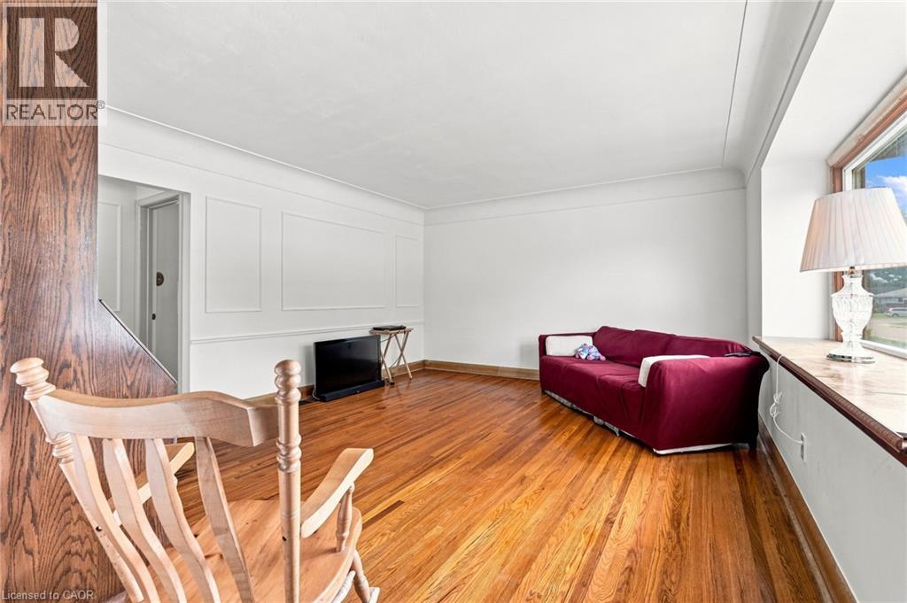 Living area featuring wood-finish flooring, wainscot wall paneling, and a deep-sill window - 241 East 44Th Street, Hamilton, ON