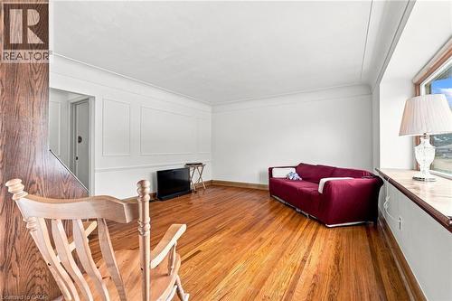 Living area featuring wood-finish flooring, wainscot wall paneling, and a deep-sill window - 241 East 44Th Street, Hamilton, ON 