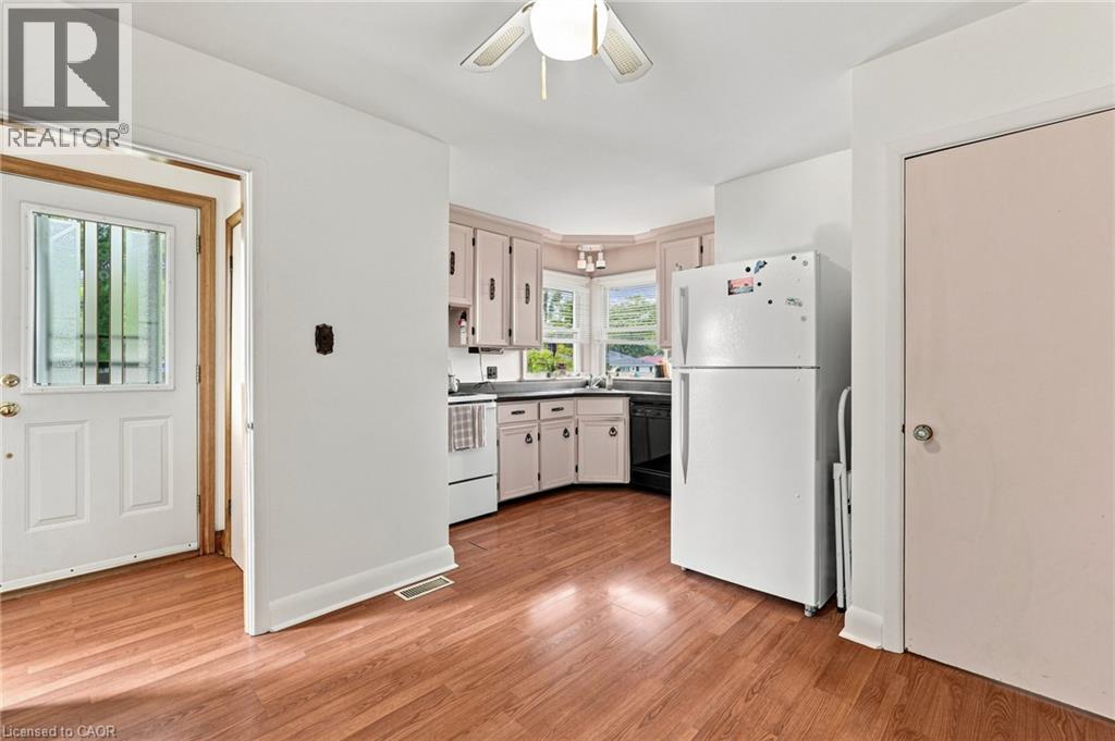 Kitchen area featuring wood-finish flooring, cabinetry with integrated hardware, a corner window configuration, and a ceiling-mounted light fixture - 241 East 44Th Street, Hamilton, ON