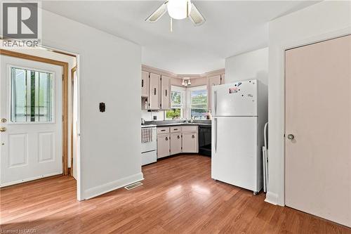 Kitchen area featuring wood-finish flooring, cabinetry with integrated hardware, a corner window configuration, and a ceiling-mounted light fixture - 241 East 44Th Street, Hamilton, ON 
