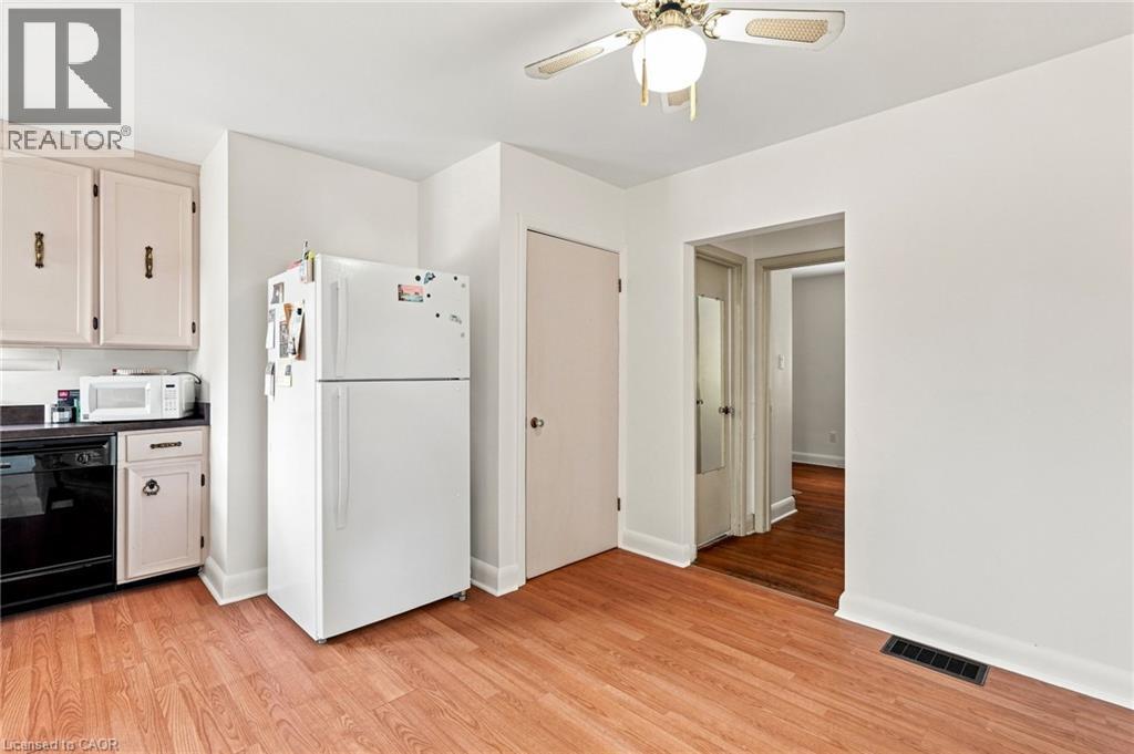Kitchen featuring light-toned cabinetry, wood-finish flooring, ceiling-mounted fan, and integrated major appliances - 241 East 44Th Street, Hamilton, ON