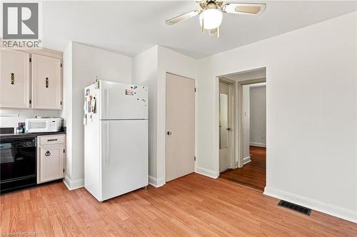 Kitchen featuring light-toned cabinetry, wood-finish flooring, ceiling-mounted fan, and integrated major appliances - 241 East 44Th Street, Hamilton, ON 