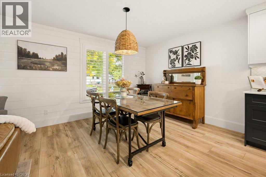 Dining area featuring horizontal shiplap wall paneling, wood-finish flooring, a woven pendant light fixture, and plantation shutters - 361 Lee Circle, Waterloo, ON