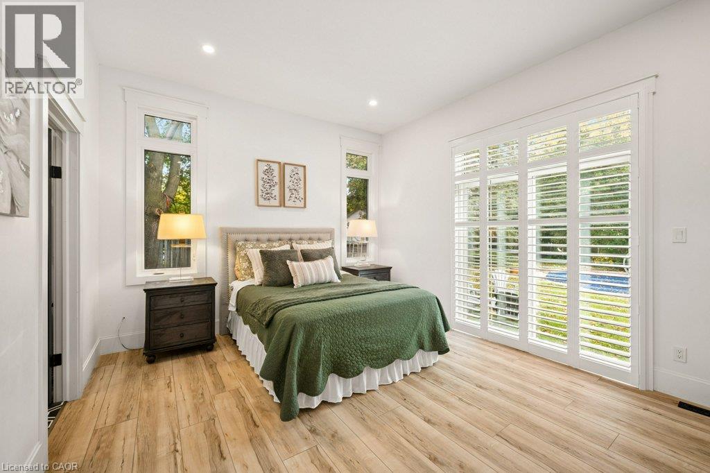 Wood-finish flooring, recessed lighting, and white plantation shutters framing a multi-panel glass door - 361 Lee Circle, Waterloo, ON
