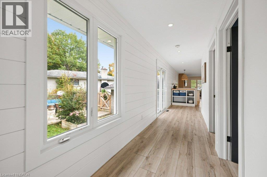 Hallway featuring horizontal shiplap wall paneling, wood-finish flooring, large double-pane windows, and recessed lighting - 361 Lee Circle, Waterloo, ON