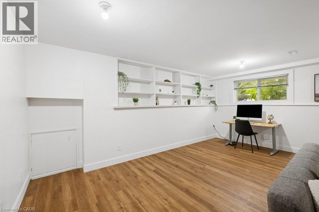 Room featuring wood-finish flooring, built-in recessed shelving, a horizontal window, and a concealed under-stair storage cabinet - 361 Lee Circle, Waterloo, ON