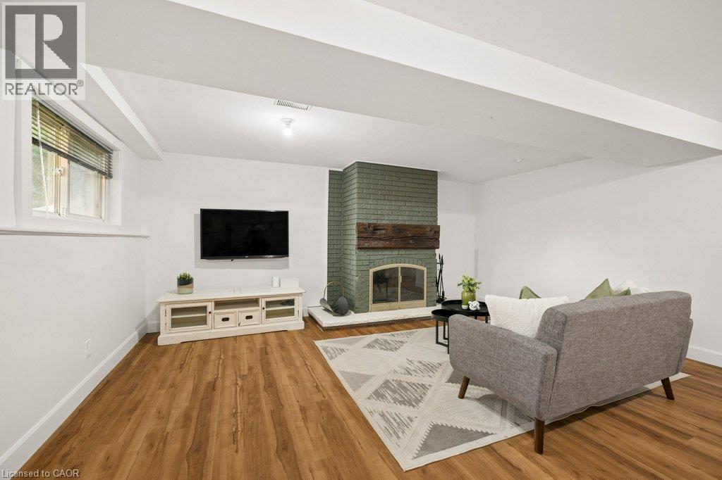 Wood-finish flooring, fireplace with a painted brick surround, natural timber mantel, glass screen, and a recessed window - 361 Lee Circle, Waterloo, ON