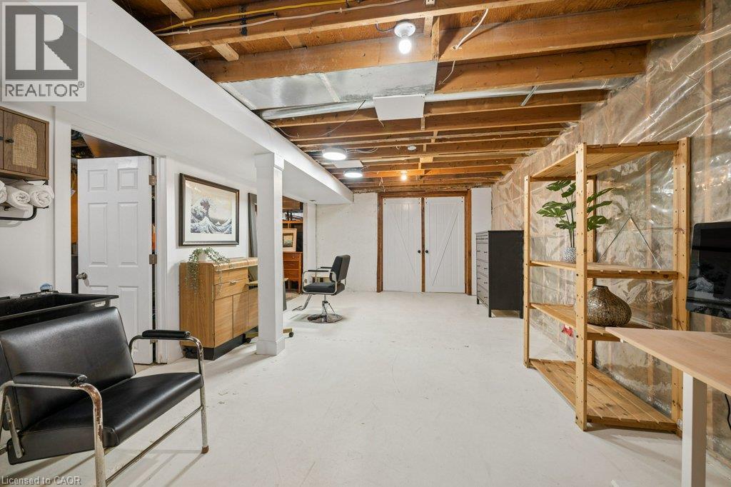 Open-concept lower level featuring exposed wood ceiling joists, painted concrete floors, white structural columns, and double-door entryway - 361 Lee Circle, Waterloo, ON