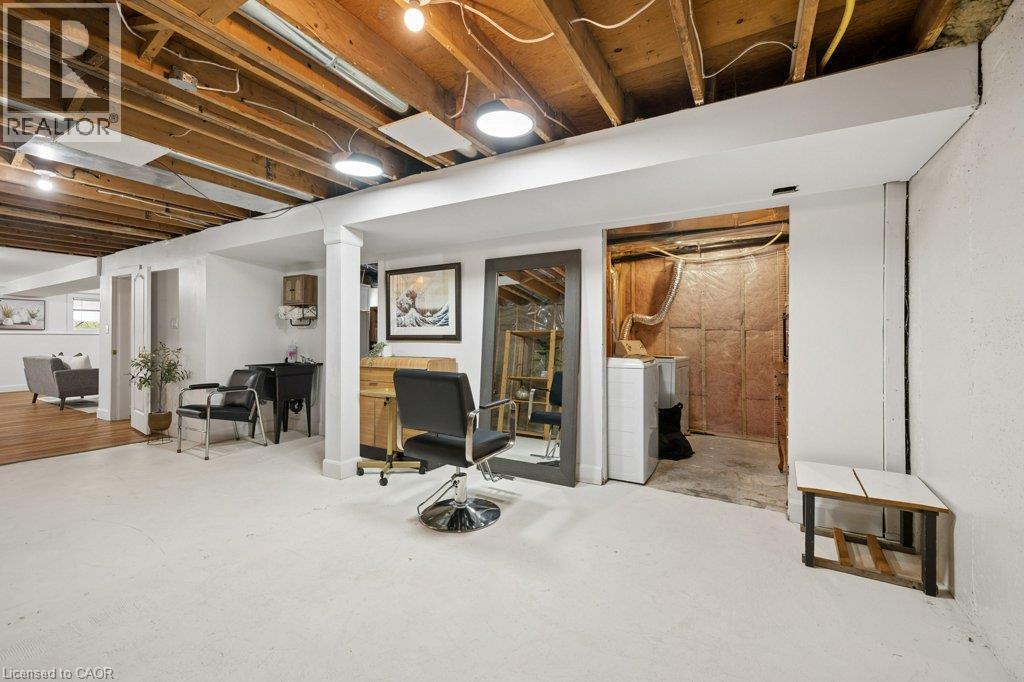 Open-concept lower level featuring exposed joist ceilings, painted concrete flooring, finished drywall, and a dedicated laundry area - 361 Lee Circle, Waterloo, ON