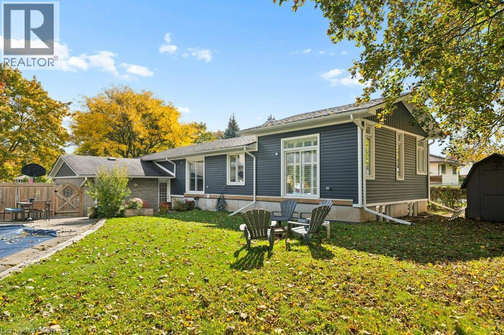 Exterior featuring dark horizontal siding, stone foundation skirting, a roof with shingle finish, and a wood privacy fence - 361 Lee Circle, Waterloo, ON