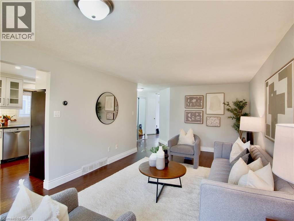 Neutral-toned interior featuring wood-finish flooring, ceiling-mounted light fixtures, and white cabinetry with stainless steel appliances - 449 Exmoor Street, Waterloo, ON
