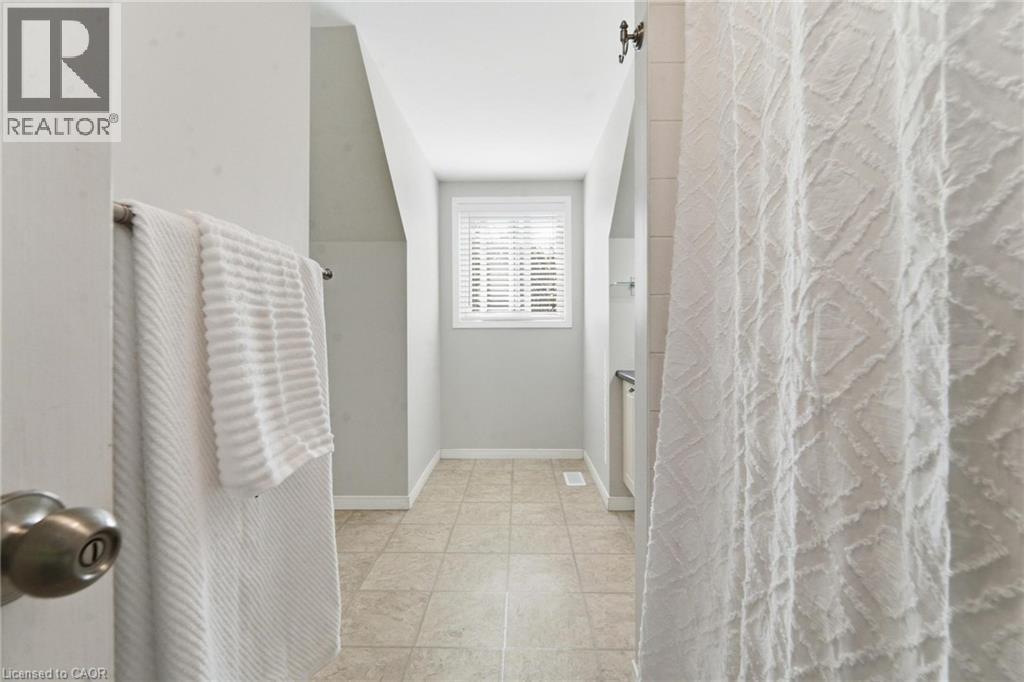 Neutral-toned interior featuring ceramic tile flooring, a window with horizontal blinds, and angled wall architecture - 449 Exmoor Street, Waterloo, ON