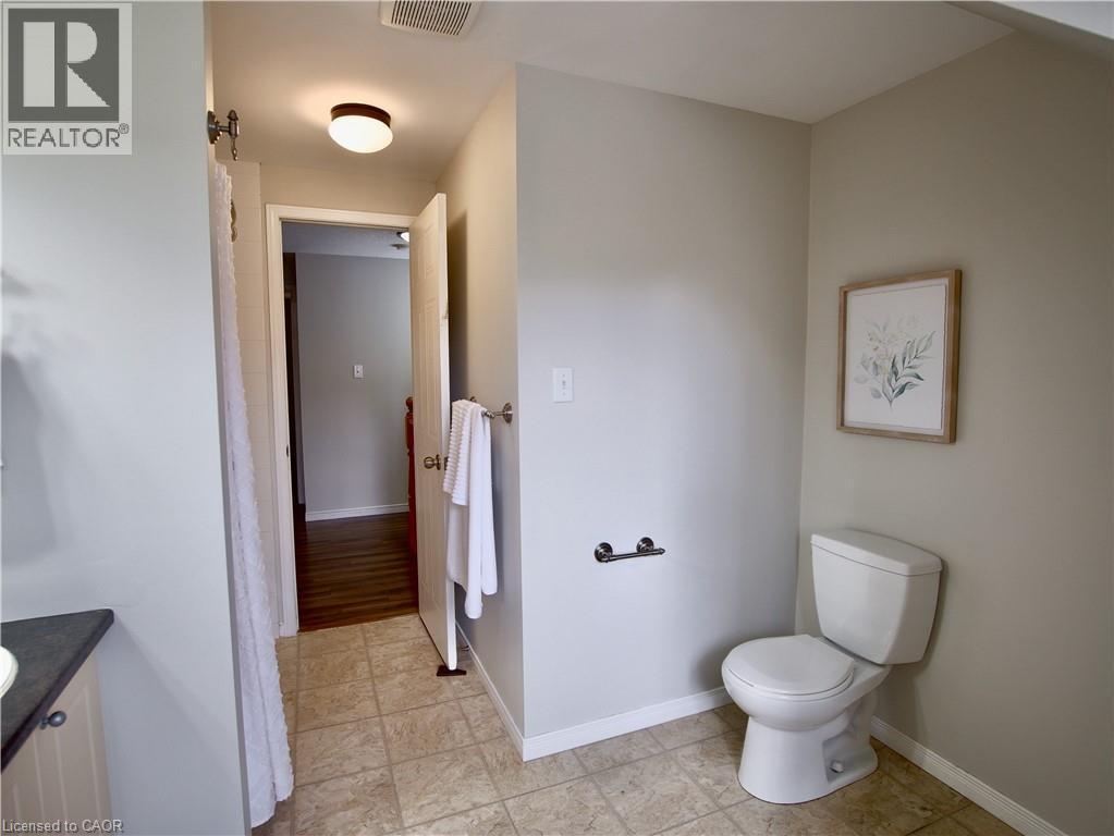 Bathroom featuring tile flooring, a two-piece toilet, a dark-toned vanity countertop, and a ceiling-mounted flush light fixture - 449 Exmoor Street, Waterloo, ON