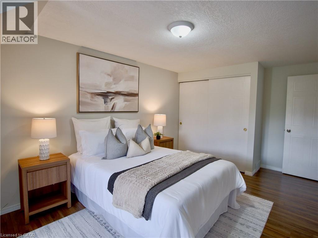 Neutral-toned interior featuring wood-finish flooring, sliding closet doors, and a ceiling-mounted light fixture - 449 Exmoor Street, Waterloo, ON