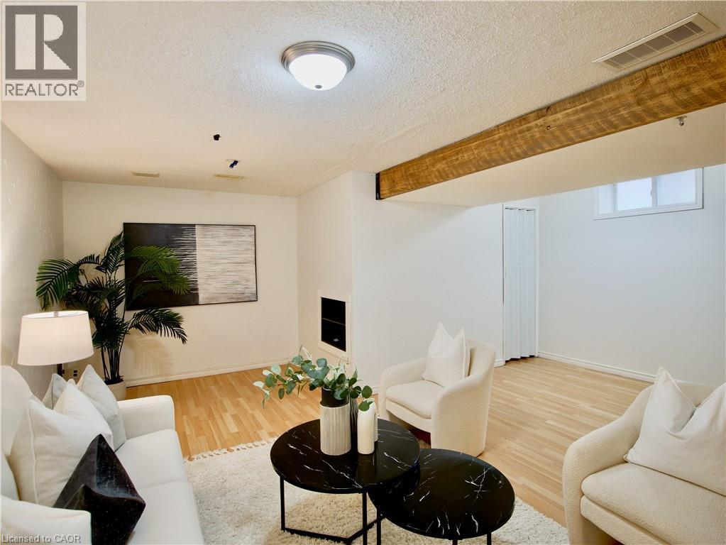 Interior space featuring wood-finish flooring, exposed natural wood ceiling beam, and wall-integrated fireplace - 449 Exmoor Street, Waterloo, ON