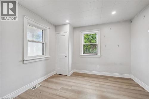 Interior space featuring light-toned wood-finish flooring, recessed lighting, neutral wall paint, and two single-pane windows with traditional casing - 1279 Hamilton Street, Cambridge, ON 