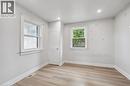 Interior space featuring light-toned wood-finish flooring, recessed lighting, neutral wall paint, and two single-pane windows with traditional casing - 1279 Hamilton Street, Cambridge, ON 