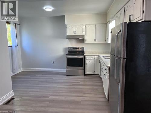 Kitchen featuring wood-finish flooring, white cabinetry, a stainless steel electric range, a stainless steel refrigerator, and a dual-basin sink - 1279 Hamilton Street, Cambridge, ON 