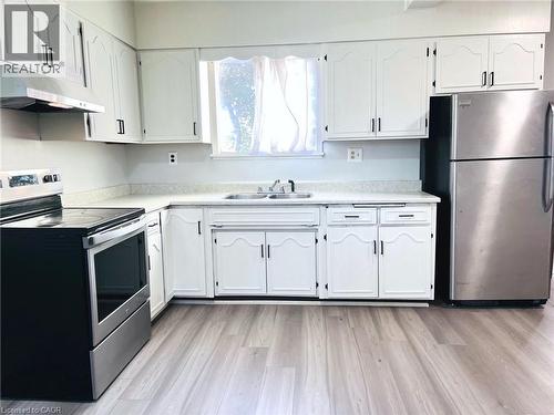 Kitchen featuring white cabinetry, light-toned countertops, stainless steel appliances, and wood-finish flooring - 1279 Hamilton Street, Cambridge, ON 